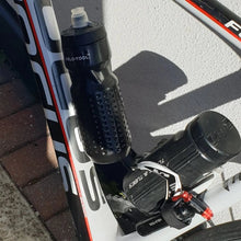 Close-up of a bicycle with a water bottle and gear system on a textured surface.