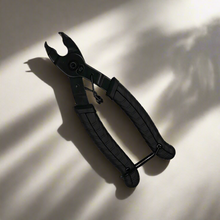 Black multi-tool on a light surface with shadows