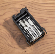 Multitool with various tools in a black case on a wooden surface
