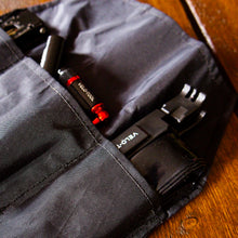Black tool roll with tools on a wooden surface