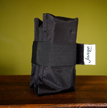Black tactical pouch with a visible brand label on a wooden surface and green background