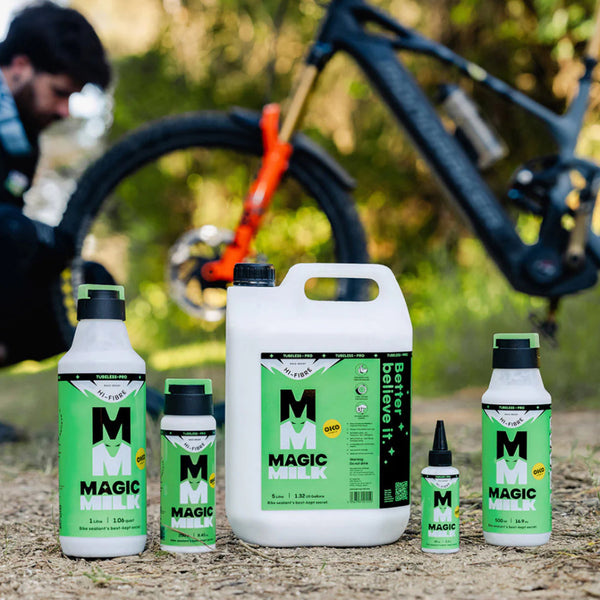 Collection of Magic Milk bottles in various sizes with a blurred background of a person and bicycle.