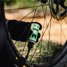 Person applying a tube of oko tyre sealant to a bicycle tyre.