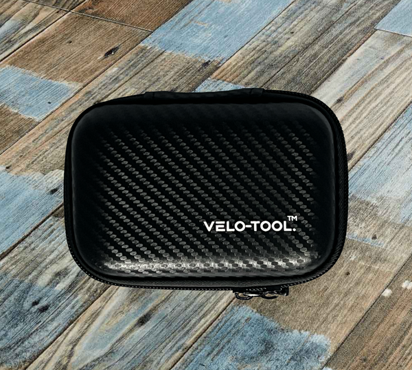 Black carbon fiber-patterned case with 'VELO-TOOL' branding on a wooden surface